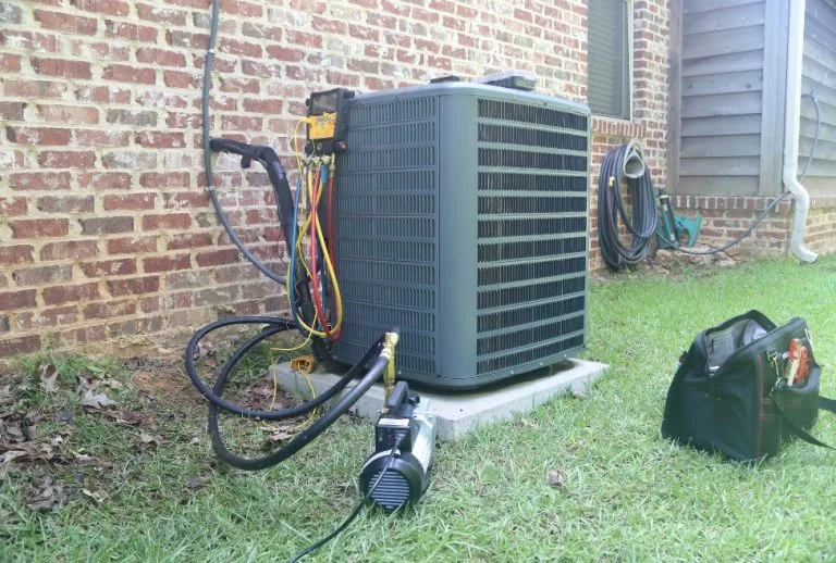 An air conditioner undergoing maintenance and repair with gauges and a vacuum pump, addressing common issues like why an
