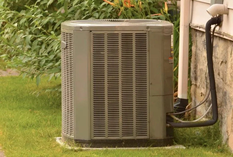 Air conditioner outside a home in a residential neighborhood during summer, representing urgent 24/7 AC repair services 
