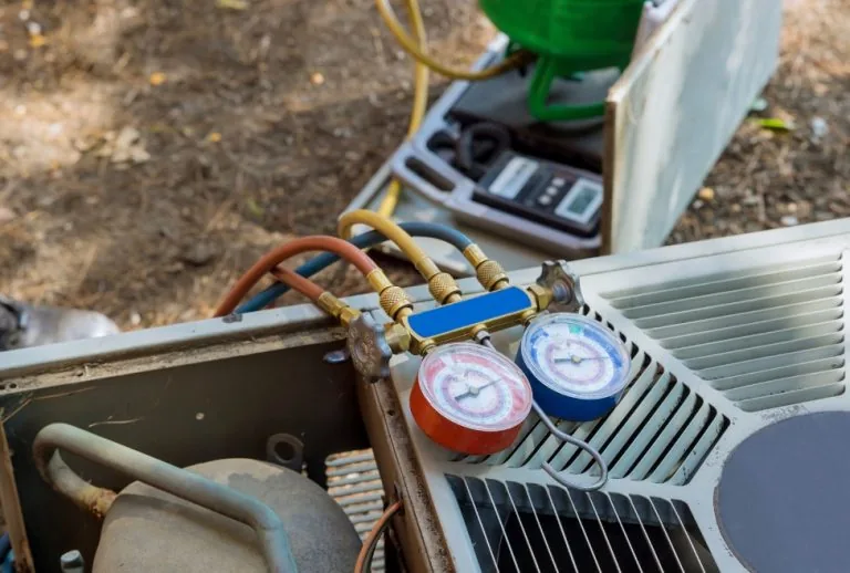 Air conditioner heating unit receiving a professional tune-up, checking refrigerant levels outside a residential home, a
