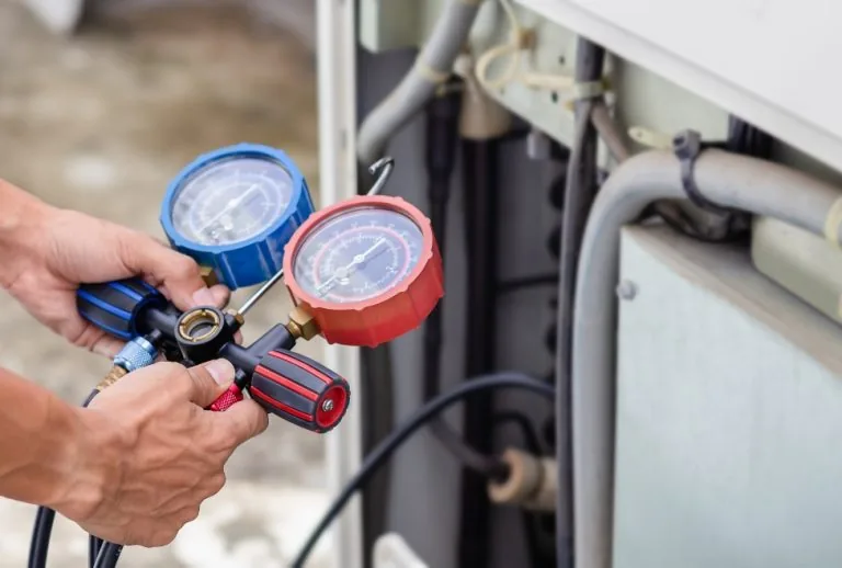 HVAC technician checking refrigerant levels and adding refrigerant using gauges, highlighting essential maintenance prac