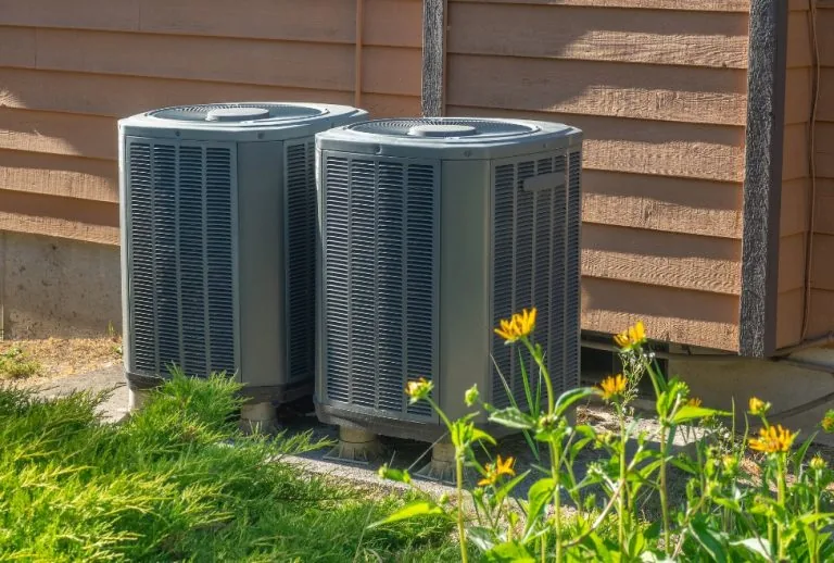 Air conditioning units outside a home, essential for heating and cooling systems, with regular HVAC maintenance to impro