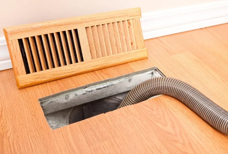 HVAC technician using a hose for professional duct cleaning to improve air quality and furnace efficiency in Salt Lake C