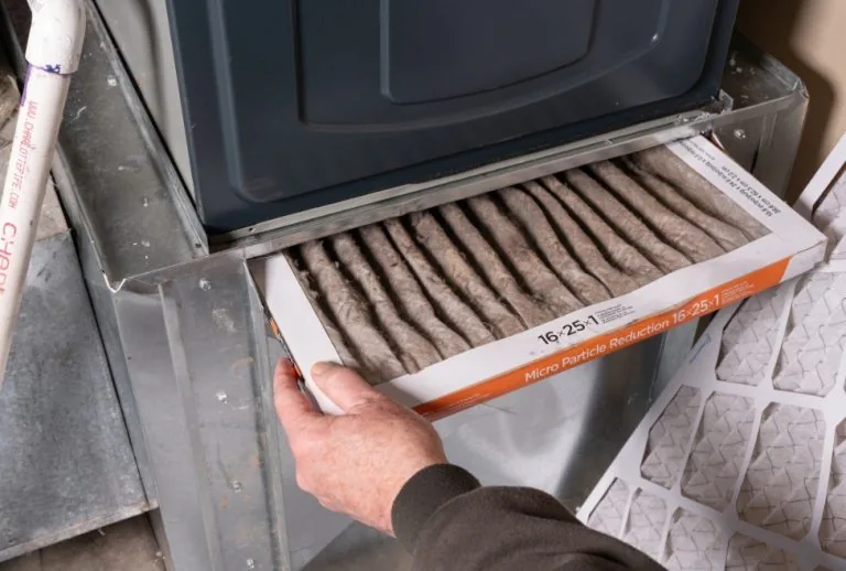 Technician replacing a dirty furnace filter during furnace maintenance service, preventing furnace breakdowns and improv