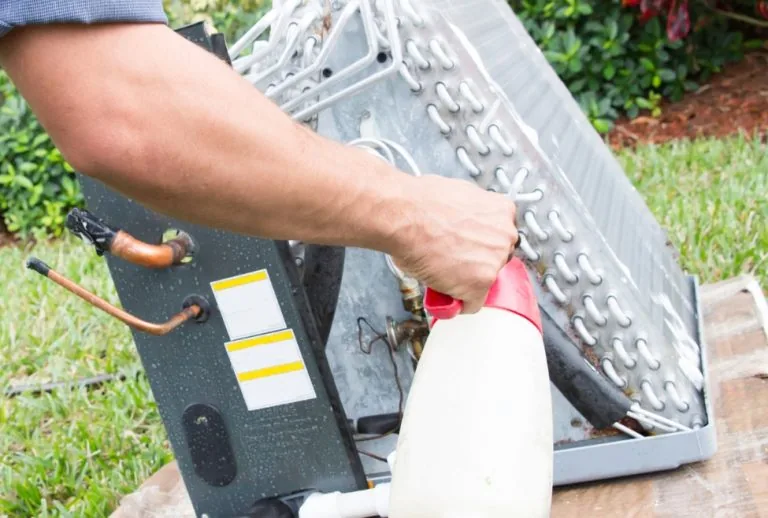 HVAC technician cleaning AC coils to remove musty smell, mold, and mildew buildup. Paradise Heating and Air provides pro
