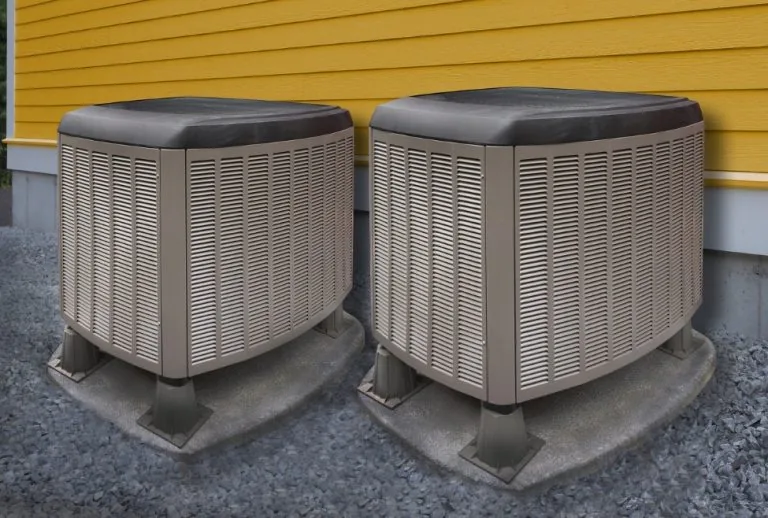 Residential HVAC air conditioning units behind a house, representing AC repair services for an air conditioner not blowi