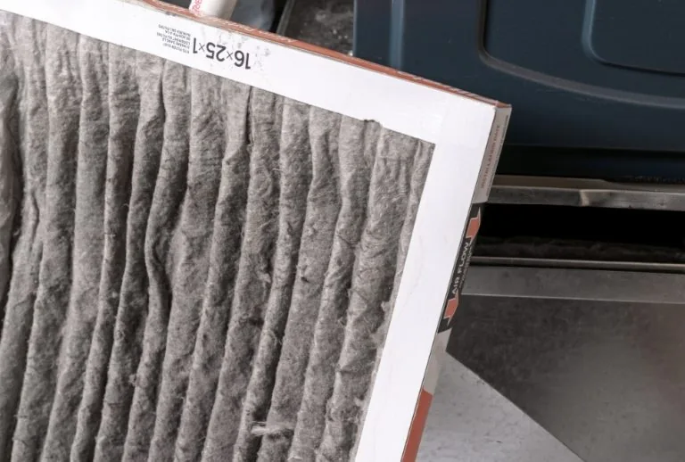 Homeowner replacing a dirty furnace filter to improve air quality and heating efficiency. Paradise Heating and Air offer