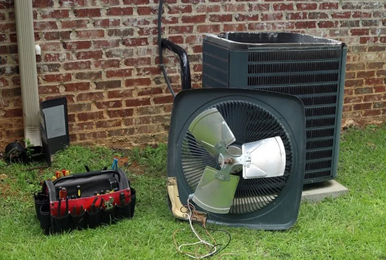 Air conditioner coil with fan and tools during AC repair outside a residential home, showing maintenance work for short 