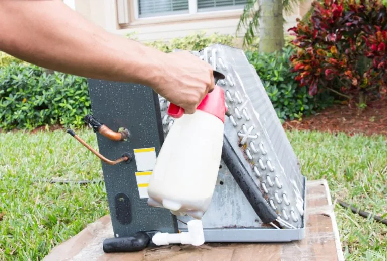 HVAC technician cleaning frozen evaporator coils on a residential AC unit, showing how to fix a frozen evaporator coil, 