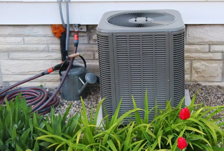 New residential HVAC system installed outside a home with red flowers, representing HVAC installation costs, energy-effi