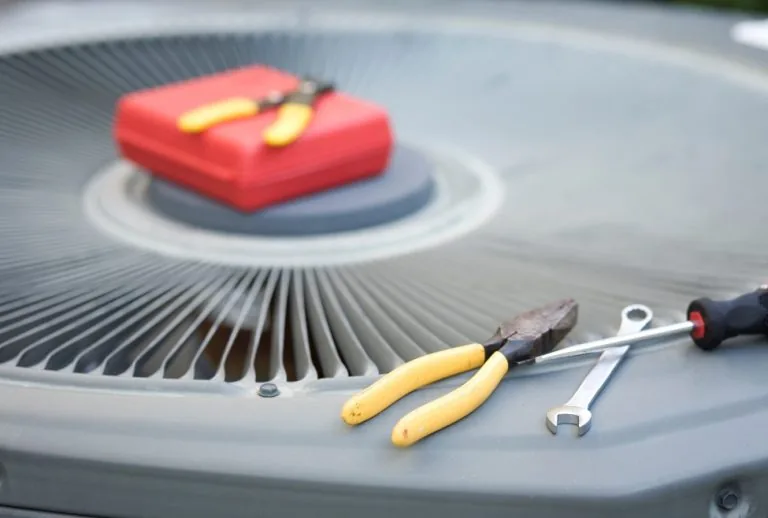 HVAC technician servicing an air conditioner with tools on top, diagnosing bad AC blower motor issues, AC not blowing ai