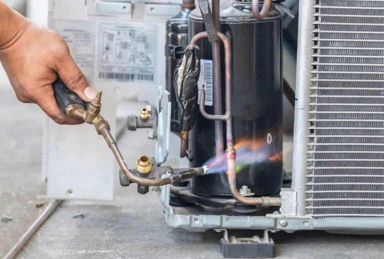 HVAC technician repairing an air conditioner capacitor, close-up view of AC unit maintenance, Paradise Heating and Air e