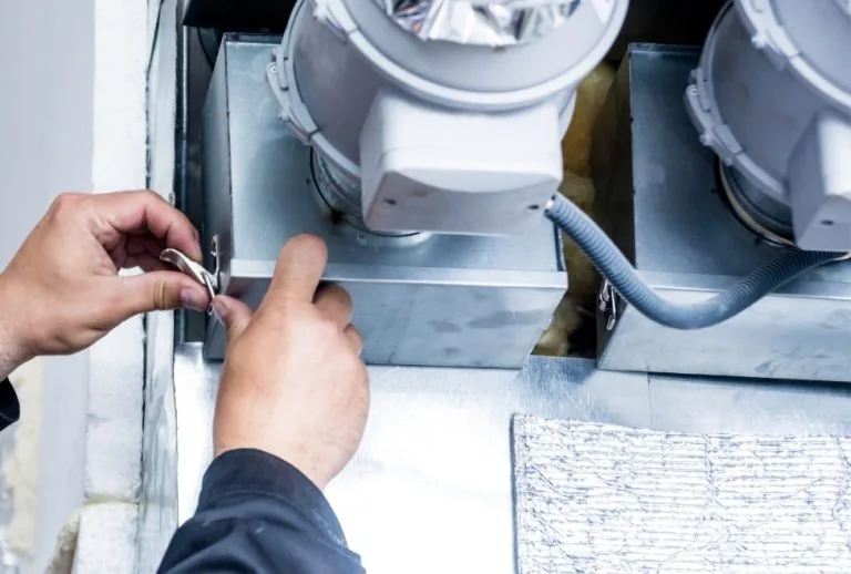 HVAC technician adjusting a manual duct damper to improve airflow in a residential HVAC system, showing proper positioni