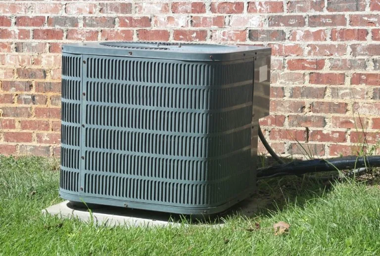 Home air conditioner in front of a brick wall showing outdoor AC unit location for condenser coil access, related to how