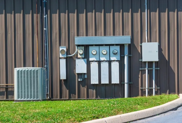 Commercial air conditioner next to electrical meters outside a building, highlighting issues like AC running but not coo