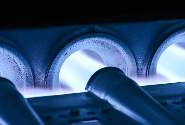 A close-up of a furnace burner which is affected by flame sensors, showing when cleaning or replacement may be needed — 