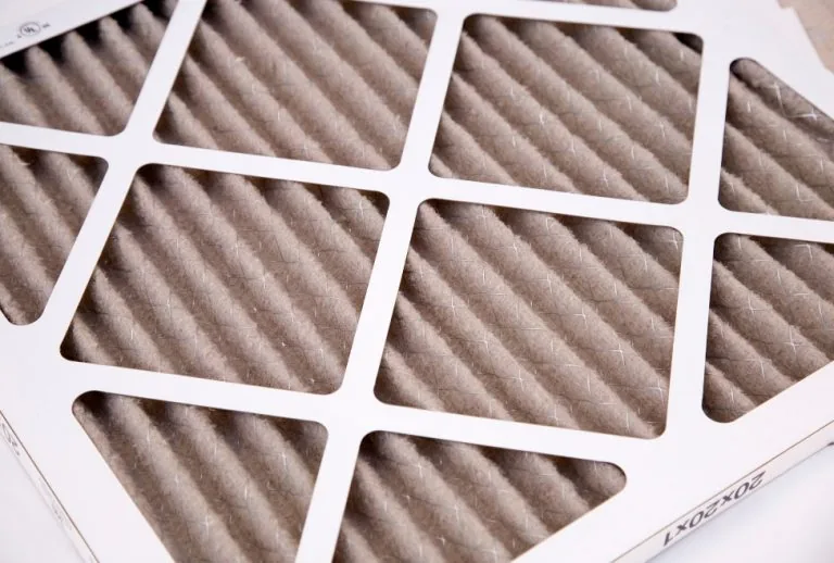 A clean furnace filter being installed in a home HVAC system, demonstrating how to change a furnace filter to improve in