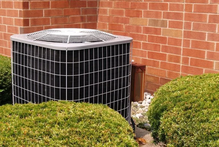 Outdoor air conditioning unit showing signs of a bad AC capacitor, including AC not turning on, clicking noises, and wea